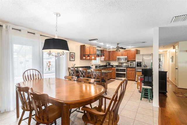 tiled dining area with ceiling fan and a textured ceiling