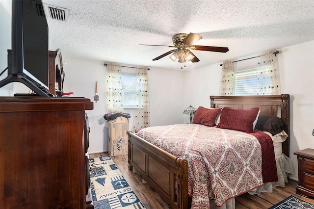 bedroom with hardwood / wood-style flooring, ceiling fan, and a textured ceiling