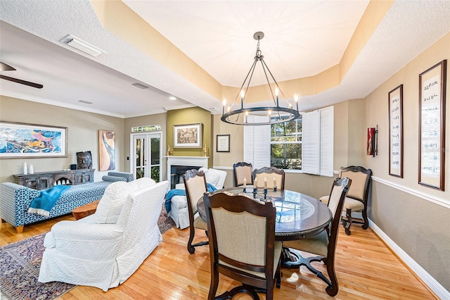 dining area featuring crown molding, light wood-type flooring, and ceiling fan with notable chandelier