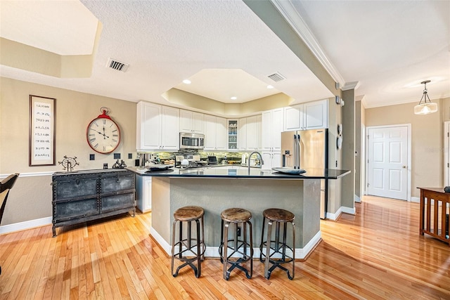 kitchen featuring light hardwood / wood-style floors, a breakfast bar, white cabinets, and stainless steel appliances