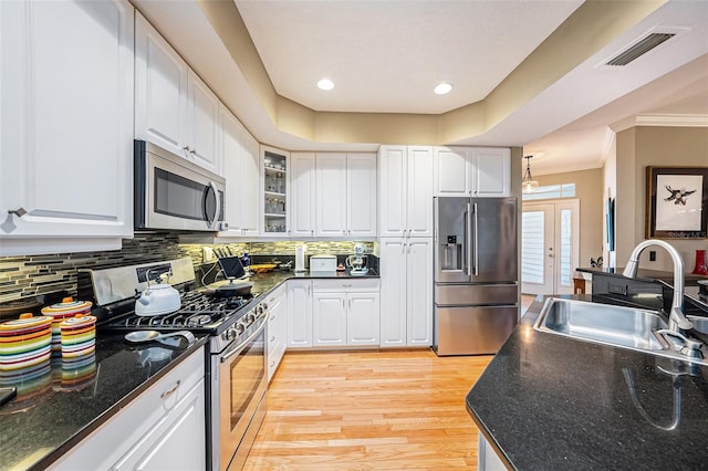 kitchen with backsplash, sink, light wood-type flooring, stainless steel appliances, and white cabinets