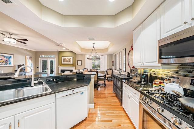 kitchen with white cabinetry, appliances with stainless steel finishes, a raised ceiling, decorative light fixtures, and sink