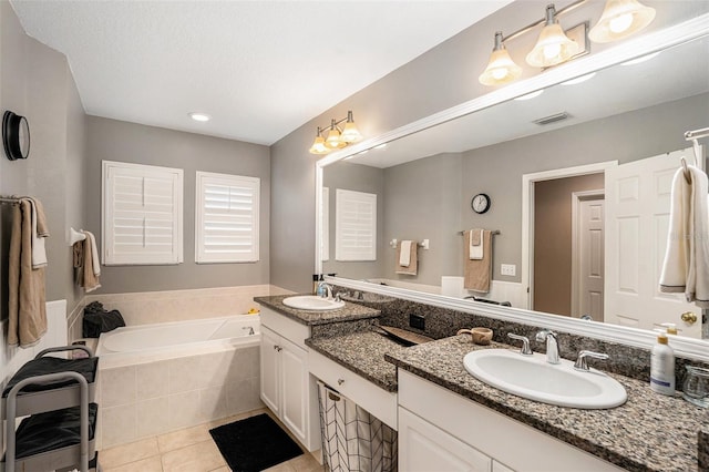 bathroom featuring tile patterned flooring, tiled tub, and vanity