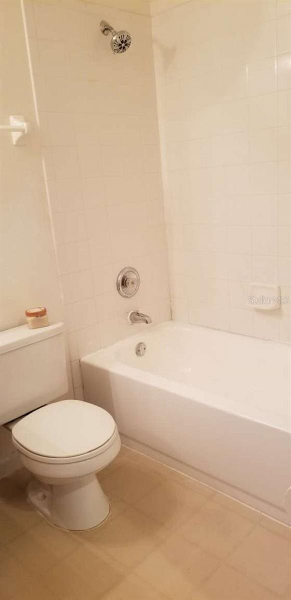 bathroom featuring toilet, tiled shower / bath, and tile patterned flooring