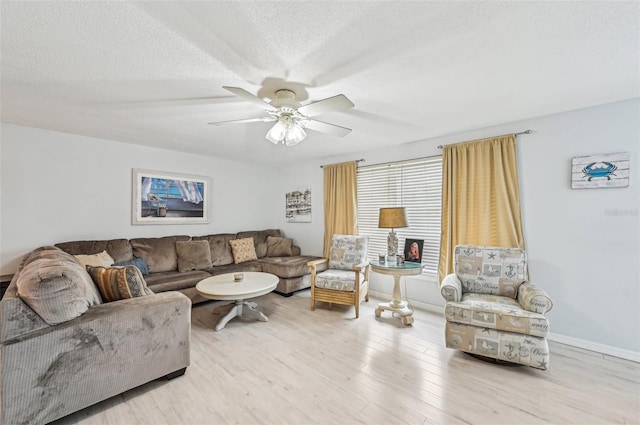 living room with ceiling fan, a textured ceiling, and light hardwood / wood-style flooring