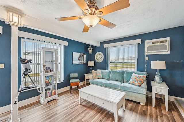 living room featuring ornate columns, a wall mounted AC, a textured ceiling, ceiling fan, and hardwood / wood-style floors