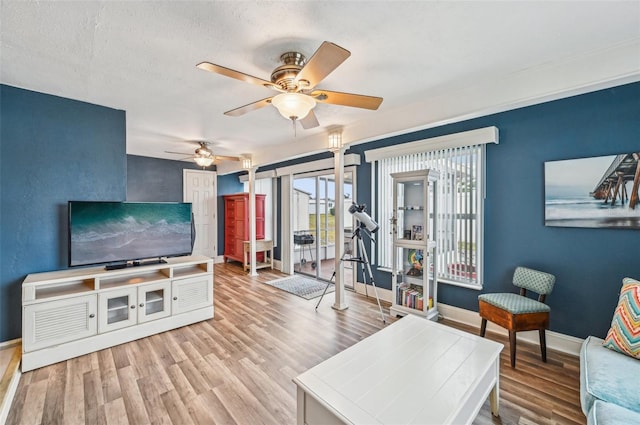 living room featuring ceiling fan, a textured ceiling, and light hardwood / wood-style floors