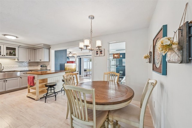 dining room with sink, a chandelier, and light hardwood / wood-style flooring