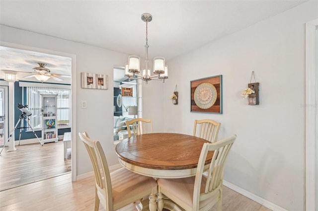 dining space with ceiling fan with notable chandelier and light hardwood / wood-style flooring