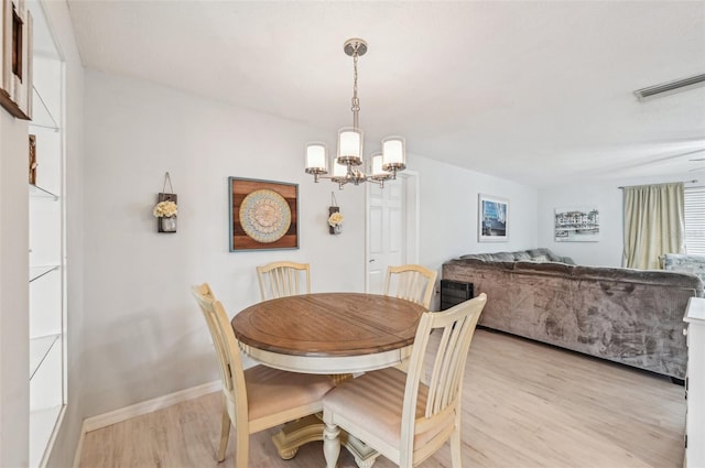 dining room with light hardwood / wood-style flooring and a notable chandelier