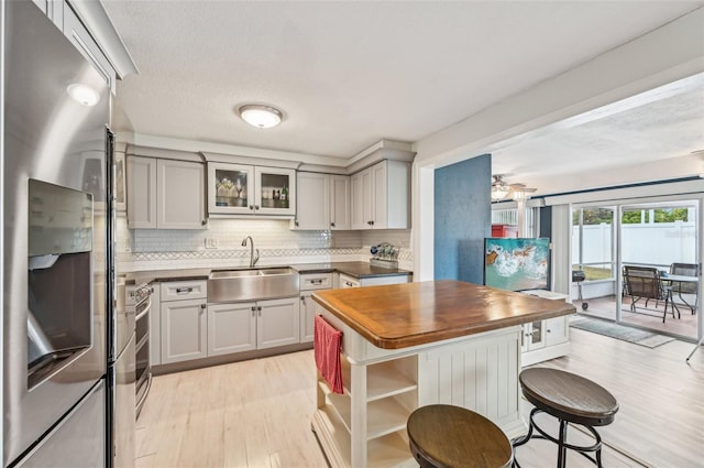 kitchen with butcher block countertops, sink, gray cabinets, appliances with stainless steel finishes, and backsplash