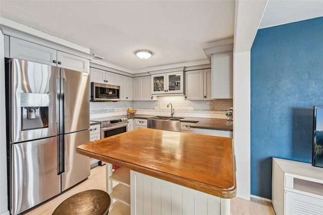 kitchen with sink, decorative backsplash, gray cabinets, and stainless steel appliances