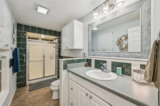 bathroom featuring vanity, tile walls, a textured ceiling, and a shower with shower door