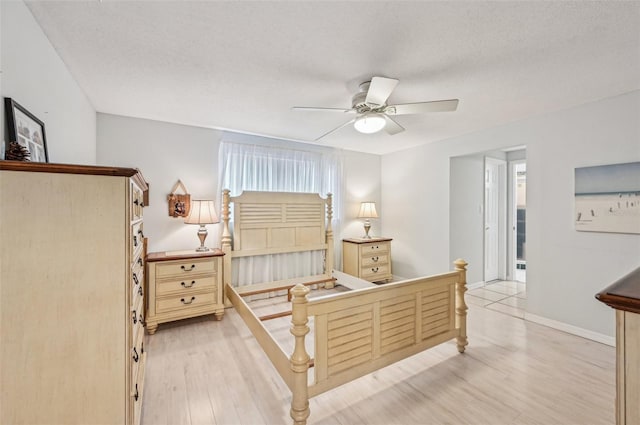 bedroom with ceiling fan, light hardwood / wood-style floors, and a textured ceiling