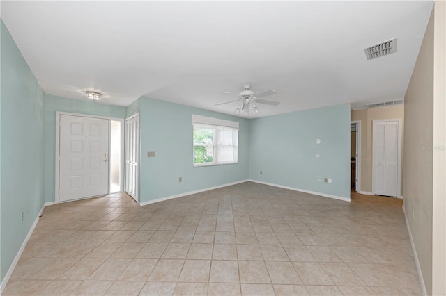 empty room featuring ceiling fan, visible vents, and baseboards