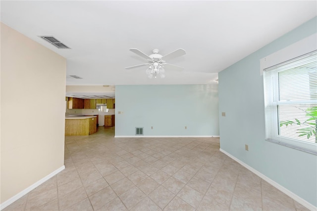 unfurnished living room with baseboards, visible vents, and a ceiling fan
