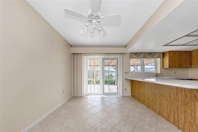 kitchen with brown cabinets, light countertops, baseboards, and light tile patterned flooring