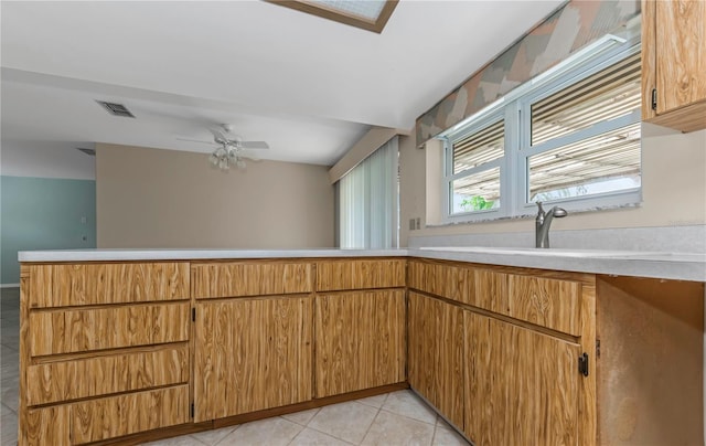kitchen featuring visible vents, brown cabinetry, a peninsula, light countertops, and light tile patterned flooring