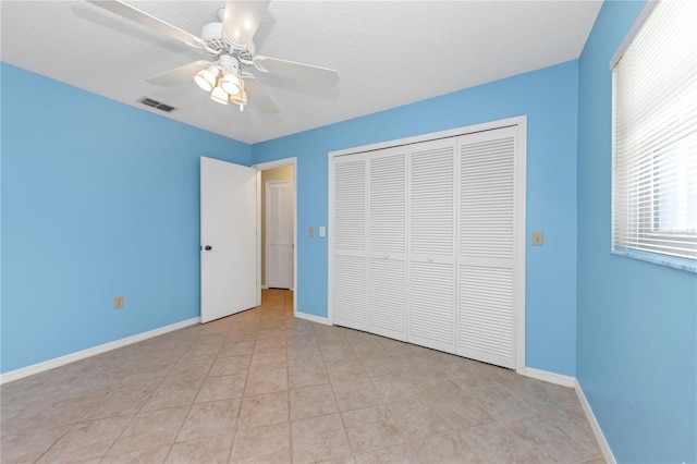 unfurnished bedroom with a closet, visible vents, a textured ceiling, and baseboards