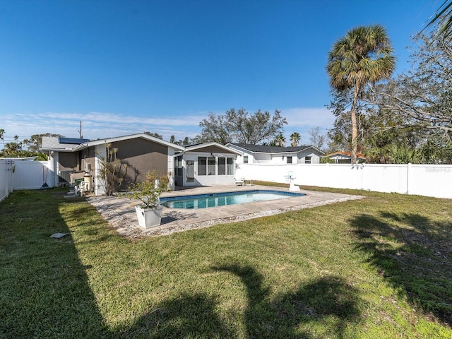 rear view of property with a lawn and a fenced in pool