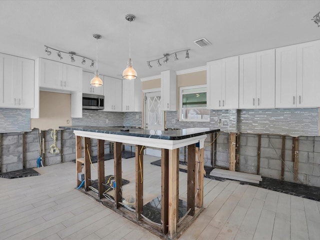 kitchen featuring decorative light fixtures, white cabinets, and crown molding