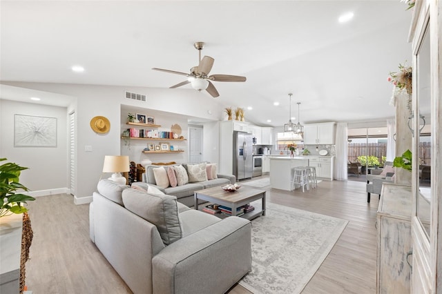 living room with lofted ceiling, ceiling fan, and light wood-type flooring