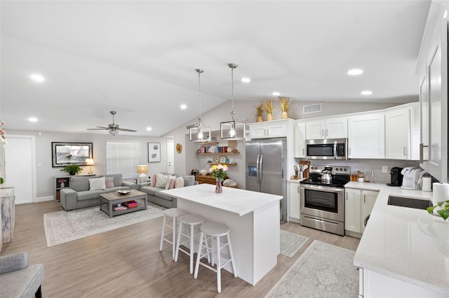 kitchen featuring appliances with stainless steel finishes, pendant lighting, tasteful backsplash, white cabinetry, and a center island