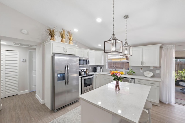 kitchen featuring tasteful backsplash, white cabinetry, appliances with stainless steel finishes, and a kitchen island