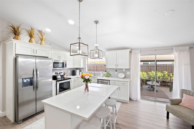 kitchen featuring pendant lighting, appliances with stainless steel finishes, white cabinetry, backsplash, and a kitchen island