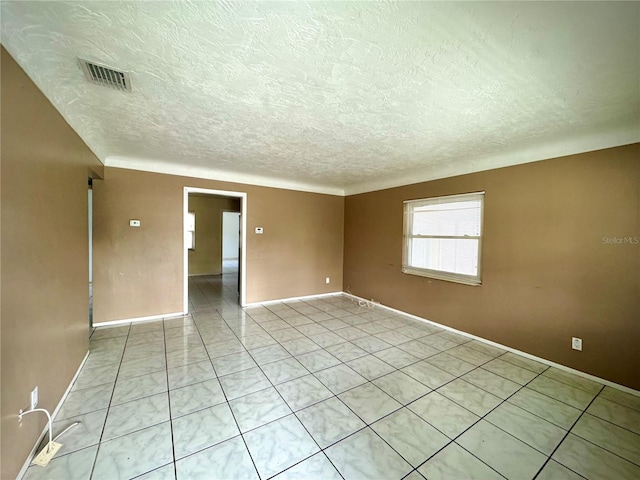 empty room featuring a textured ceiling and light tile patterned flooring