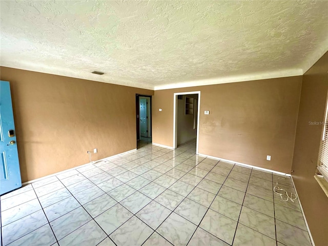 empty room featuring light tile patterned floors and a textured ceiling