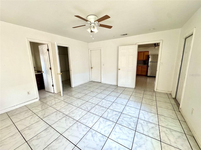 unfurnished bedroom with stainless steel refrigerator, a spacious closet, light tile patterned floors, ceiling fan, and a closet