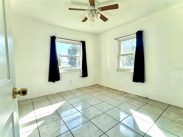 tiled spare room with ceiling fan and a textured ceiling