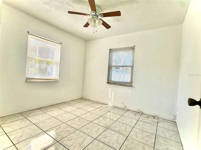 unfurnished room featuring ceiling fan, a wealth of natural light, a textured ceiling, and light tile patterned floors