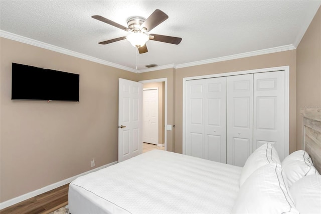 bedroom featuring ceiling fan, light hardwood / wood-style floors, crown molding, a textured ceiling, and a closet