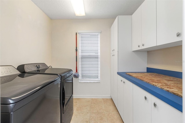 washroom featuring light tile patterned floors, cabinets, washer and dryer, and a textured ceiling