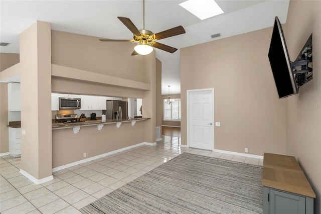 kitchen featuring white cabinets, stainless steel appliances, kitchen peninsula, light tile patterned flooring, and ceiling fan