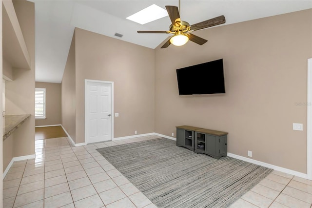 unfurnished living room featuring ceiling fan, light tile patterned floors, and vaulted ceiling with skylight