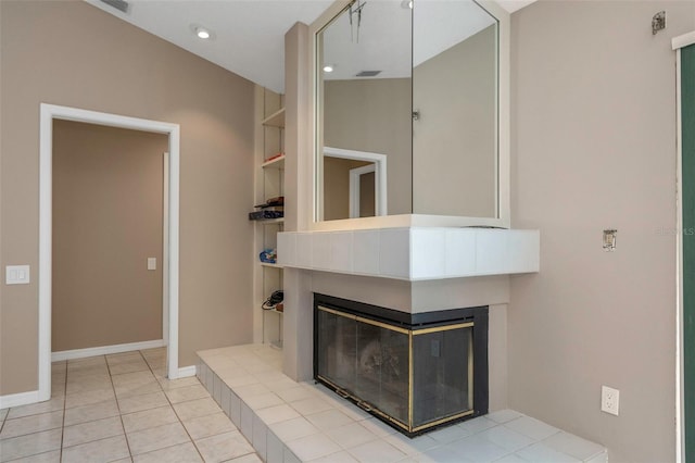 unfurnished living room featuring built in shelves, a tiled fireplace, and light tile patterned flooring