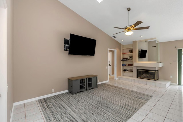 unfurnished living room with light tile patterned floors, ceiling fan, vaulted ceiling, a tile fireplace, and built in shelves