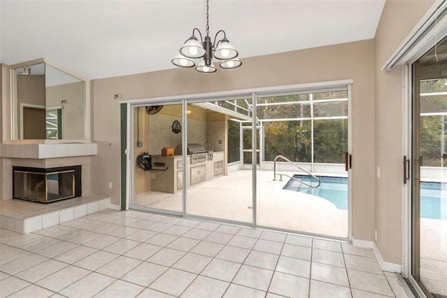 interior space featuring light tile patterned floors, a tile fireplace, and an inviting chandelier