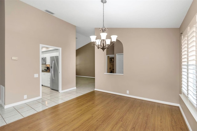 tiled spare room with lofted ceiling and an inviting chandelier