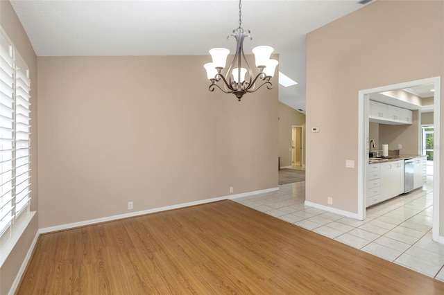 empty room with a notable chandelier, light hardwood / wood-style floors, and sink