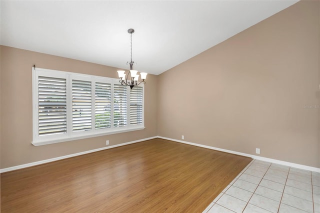 tiled spare room featuring a notable chandelier