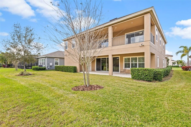 rear view of property with a balcony, a yard, and a patio