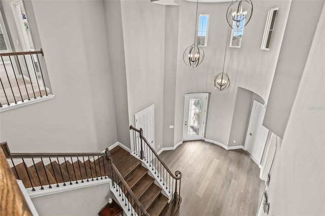 foyer entrance featuring a notable chandelier, a towering ceiling, and light wood-type flooring