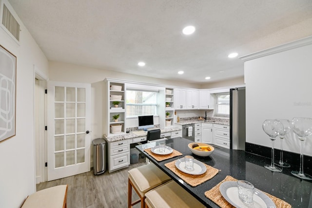 kitchen with visible vents, light wood finished floors, open shelves, white cabinetry, and fridge