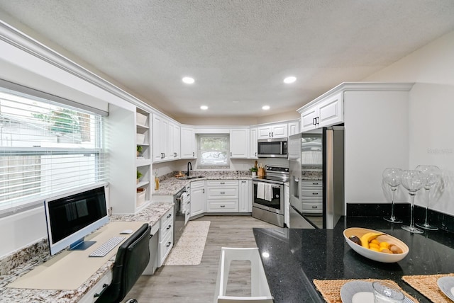 kitchen featuring open shelves, stainless steel appliances, white cabinets, a textured ceiling, and light wood-type flooring