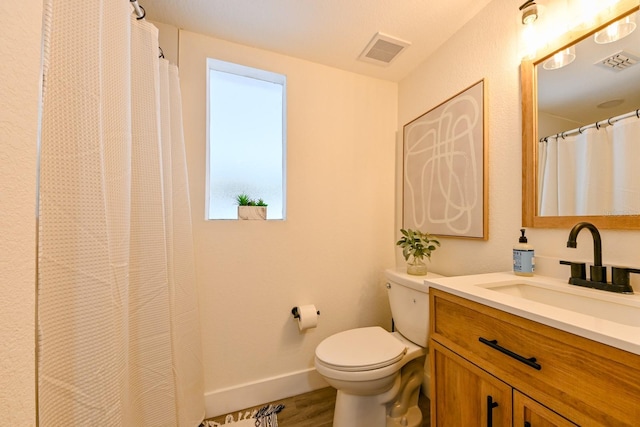 bathroom featuring visible vents, baseboards, toilet, and vanity