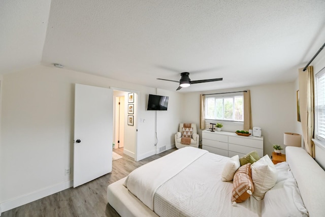 bedroom featuring baseboards, a textured ceiling, wood finished floors, and a ceiling fan